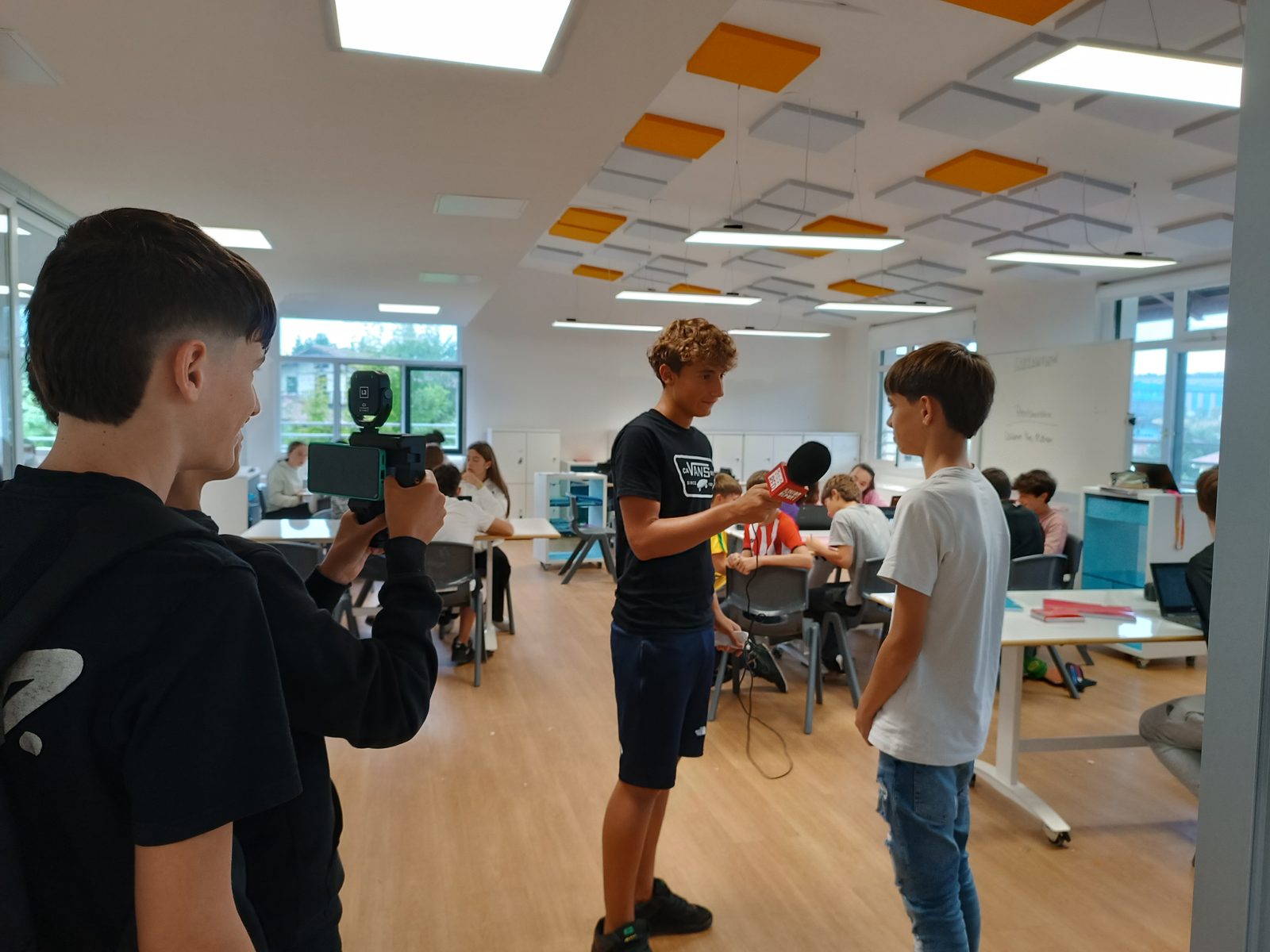 Alumnat treballant com a redactors: càmera, micròfon i entrevista a l'aula