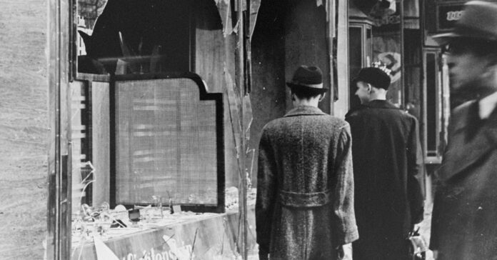 Ciutadans alemanys l'endemà de la nit dels vidres trencats, davant botigues i cases jueves destruïdes (National Archives and Records Administration, College Park)