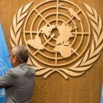 Un home col·loca una bandera de l'Organització de les Nacions Unides