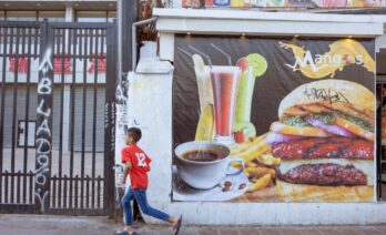 Un nen corre davant d’un cartell de menjar ràpid camí cap a una botiga de llaminadures, al centre de Santiago, Xile (UNICEF/UN0805425/Goupil)