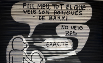 La persiana metàl·lica de la botiga Dulcidante amb un grafit d'un iceberg que diu “Les famílies que viuen de la botiga” (foto pròpia).